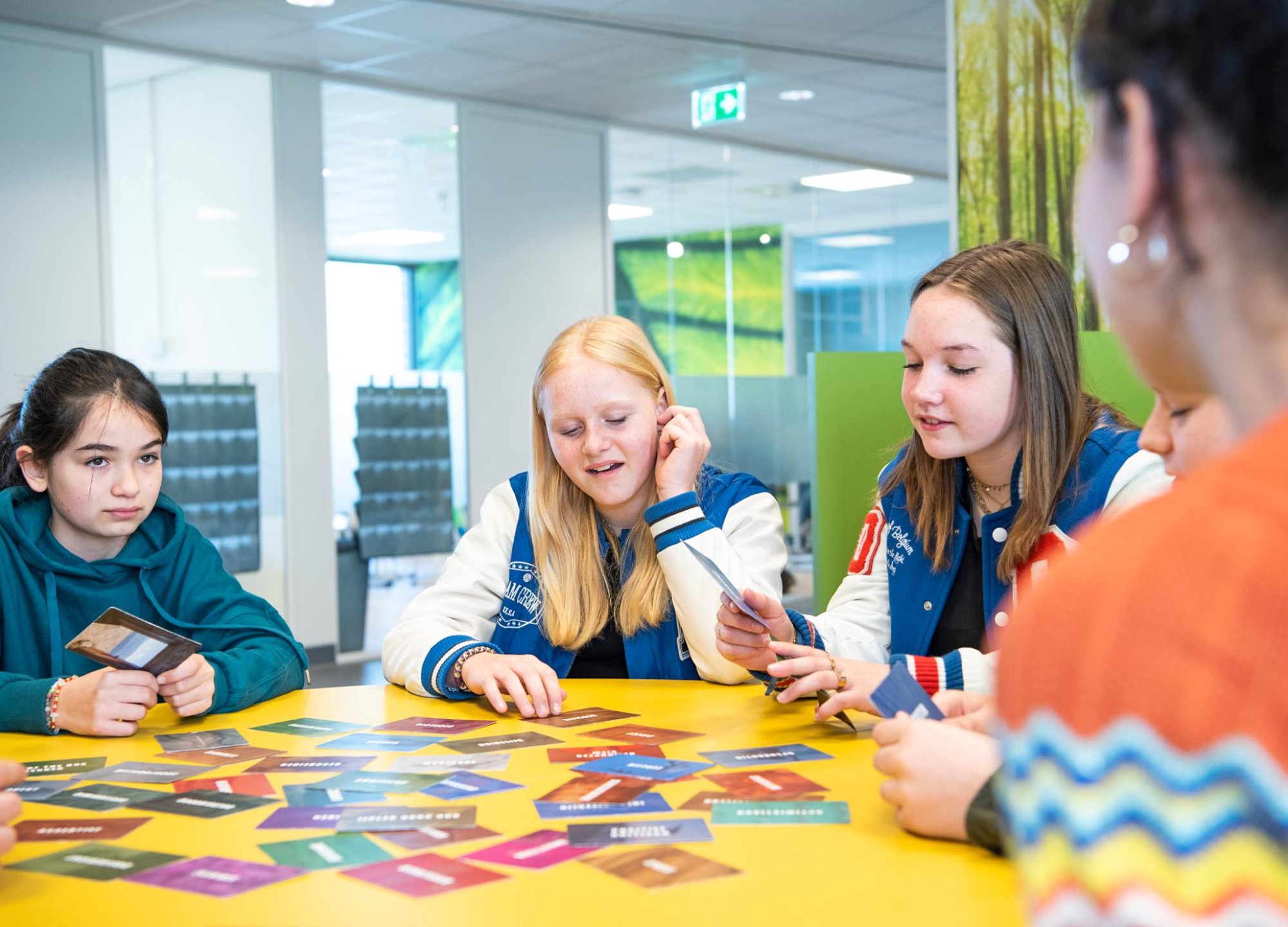 Kinderen in gesprek over het kaarspel dat voor ze op tafel ligt