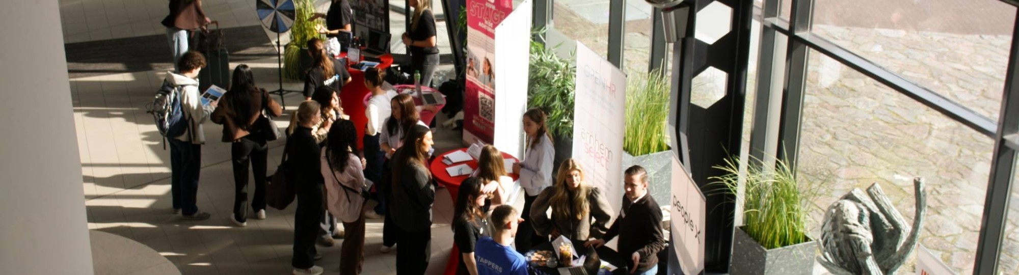 Netwerkmarkt 9 maart 2026, foto van boven genomen. Je ziet meerdere kraampjes met daarachter werkgevers en studenten die op zoek zijn naar een stage.