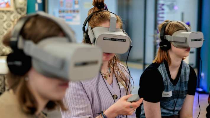 Drie vrouwen met een grijze virtual reality bril op 