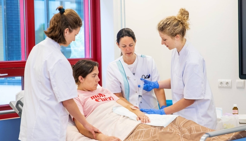 3 verpleegkundigen rondom het bed van een patiënt