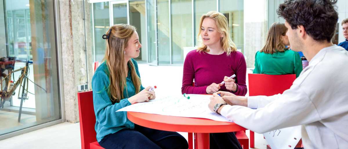 Lachende studenten aan tafel. Master Circulaire Economie 2024.