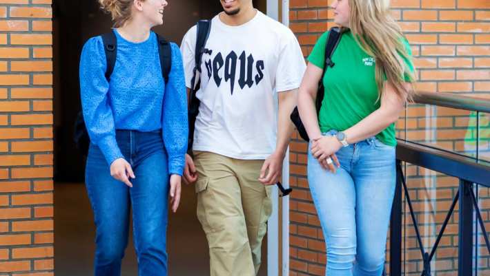 3 studenten zijn met elkaar in gesprek lopend over de brug