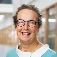 Portretfoto Marian de van der Schueren, brildragend, witte blouse, zeegroene trui