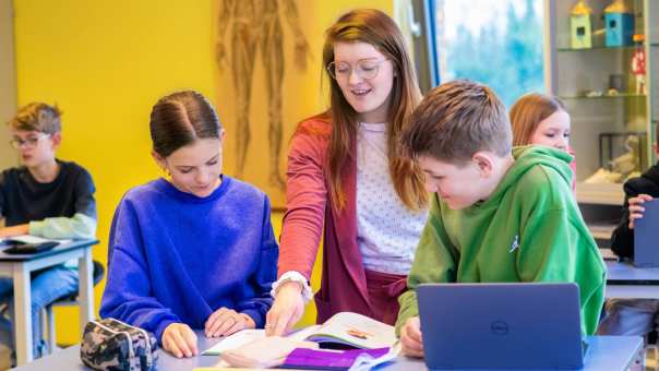 Fotoshoot op het Citadel 2024. De docente wijst in een schrift waar 2 scholieren naar kijken.