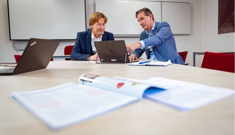 Lector Financial Control en associate lector Sustainable Finance & Tax zijn met elkaar in overleg en wijzen hierbij naar een laptop.