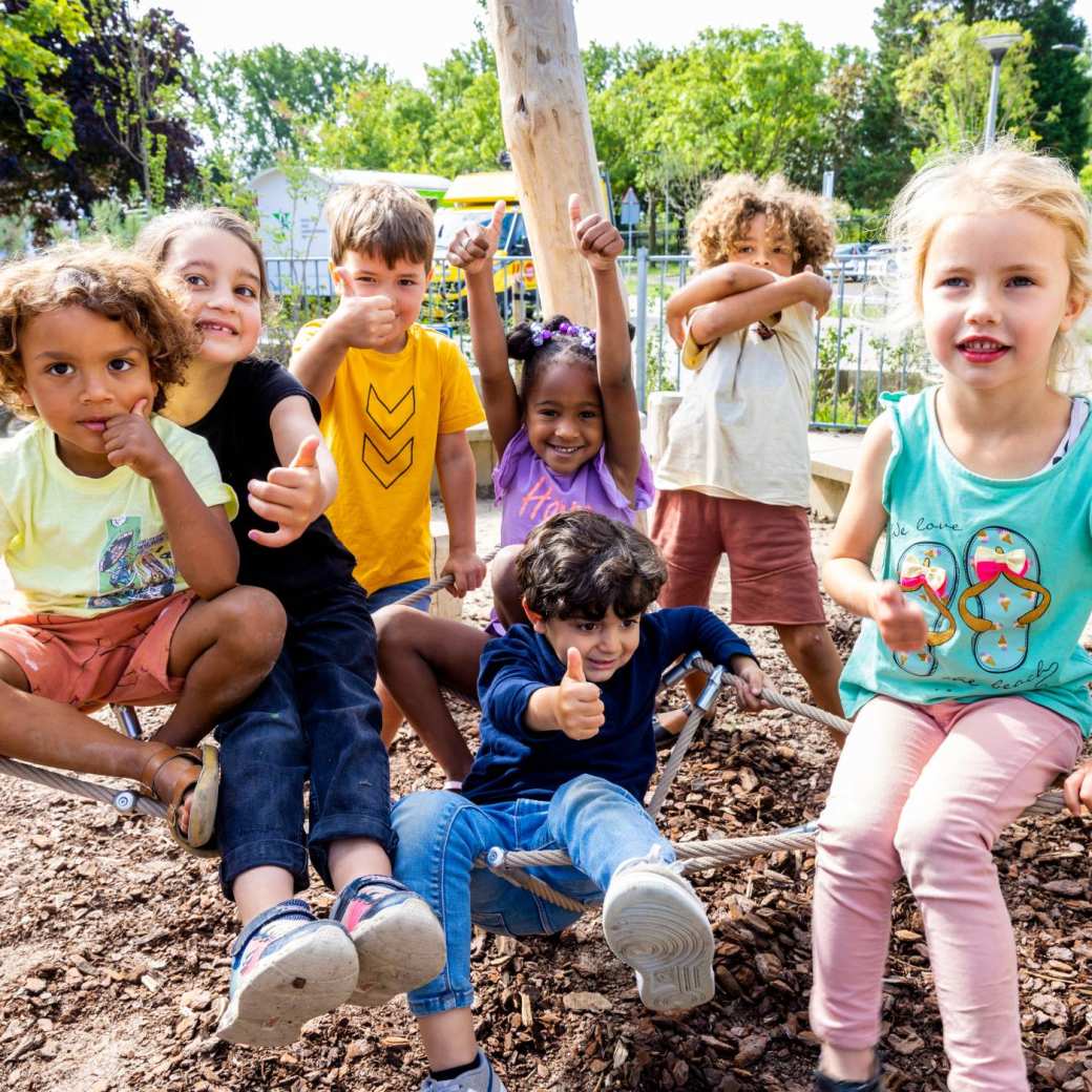 Zeven kinderen poseren buiten op het klimnet. Foto van de opleiding leraar basisonderwijs 