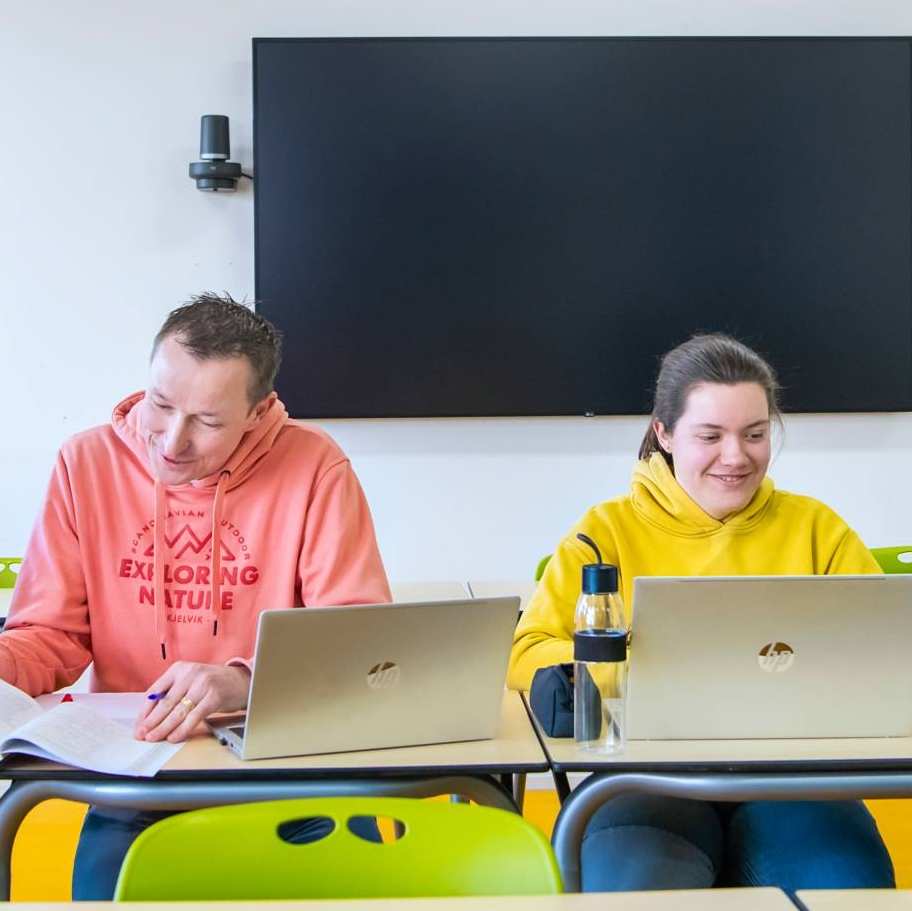 Foto Master Academie Educatie. 4 masterstudenten zitten geconcentreerd op een rij achter hun laptops aan een tafel.