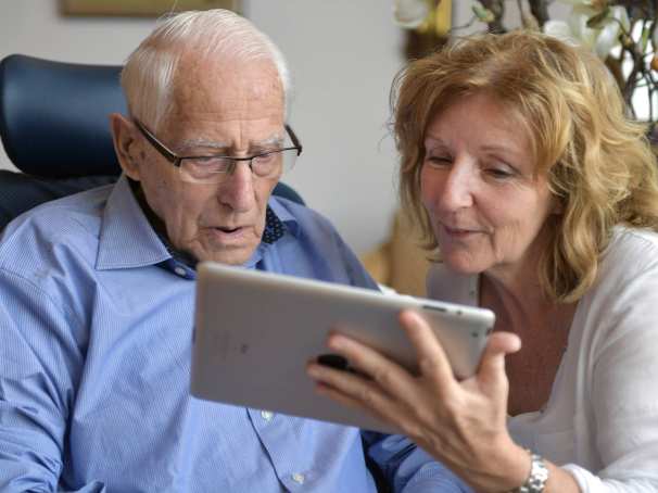 toont fotoâs op een tablet aan een bewoner van het verpleeghuis