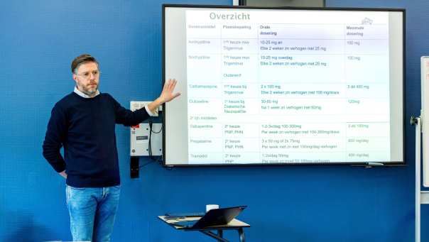 Docent wijst tekst aan op bord tijdens de cursus acute pijn service.