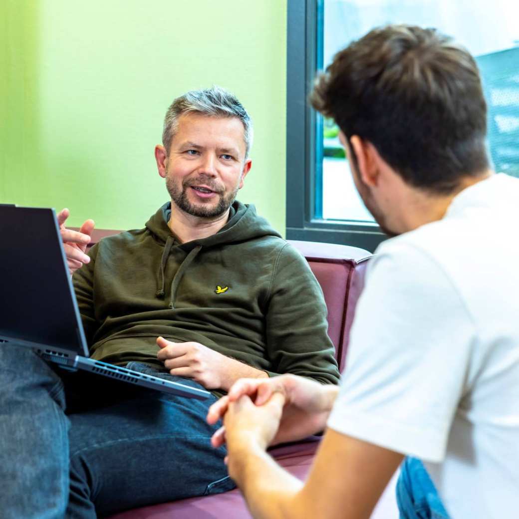 Werkgever vraagt SLIM Scholingssubsidie aan op laptop, in gesprek met werknemer.