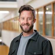 Portretfoto Pieter van Rooij, grijs t-shirt, donkere blouse erover 