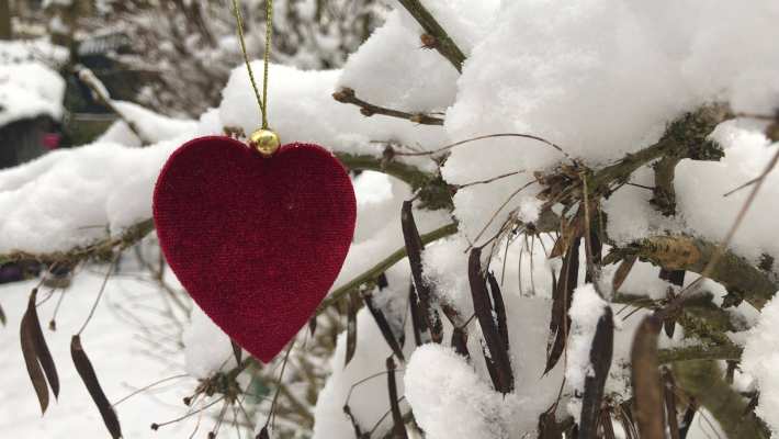 Een foto van een rood hart in de sneeuw