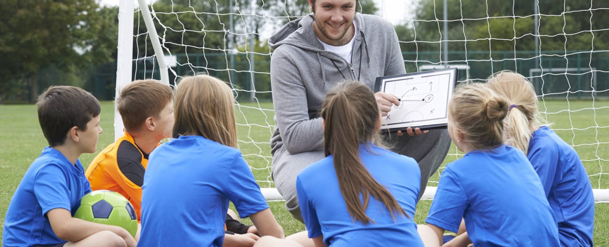sportleraar geeft team met basisschool voetbalteam instructie