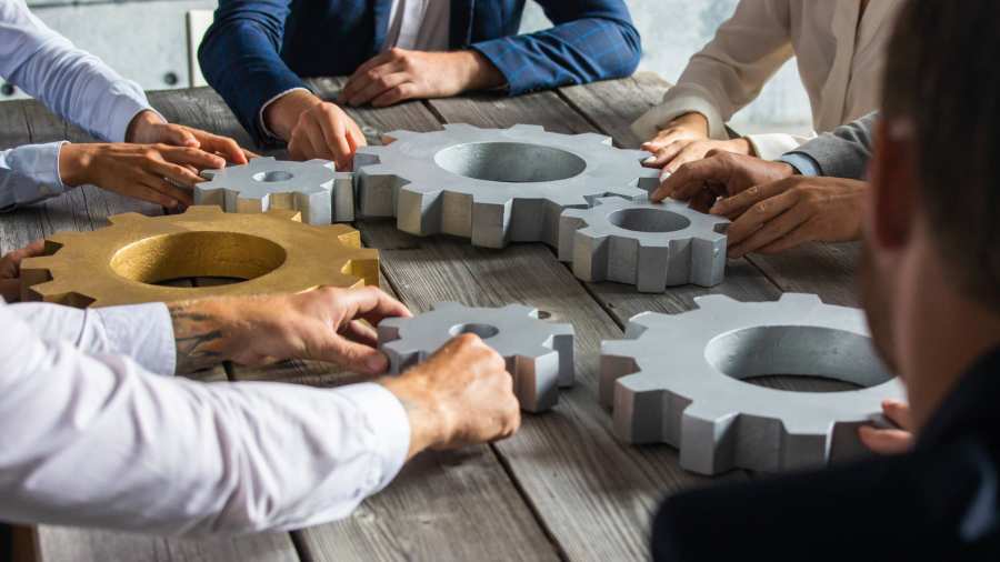 5 mensen aan een houten tafel draaien aan grote radars. Samenwerken. Seece