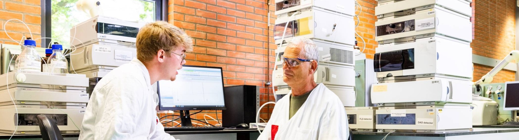 docent geeft uitleg aan student in chemie lab