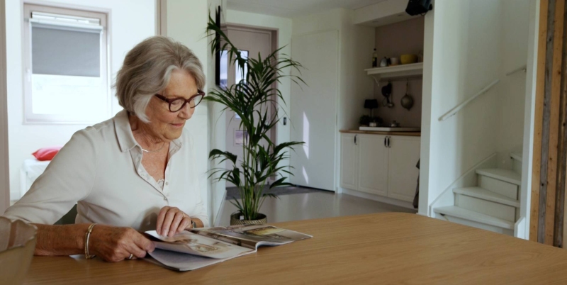 Een oudere vrouw zit aan tafel