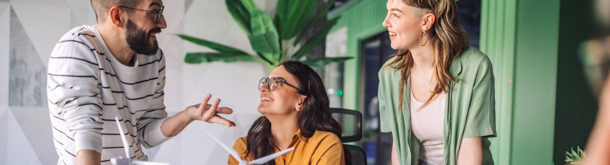 Mensen in kantoor lachen, windmolen en planten op de achtergrond