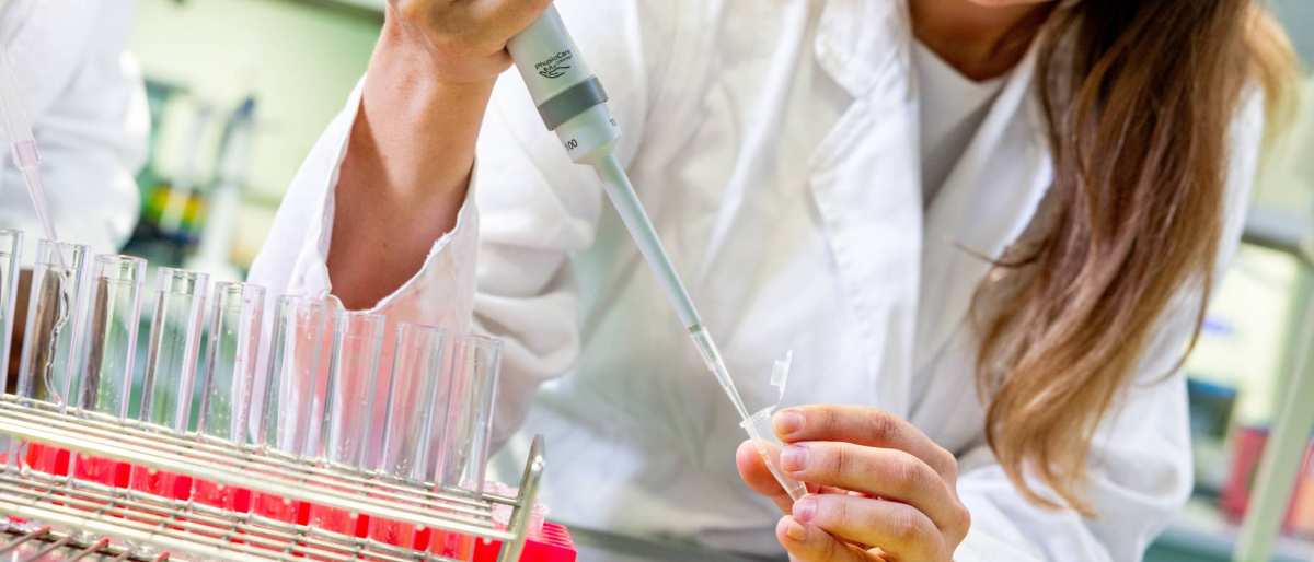 Student in het lab met reageerbuisjes en een pipet