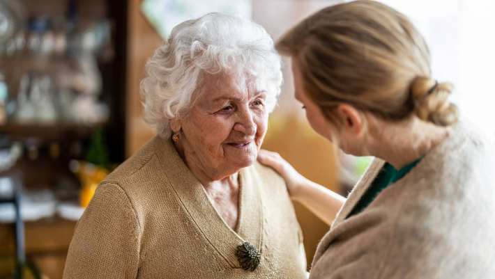 Verpleegkundige in gesprek met oudere vrouw