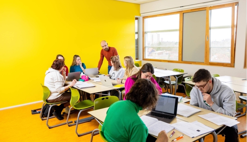 De docent loopt rond in het klaslokaal. De studenten zijn aan het werk.