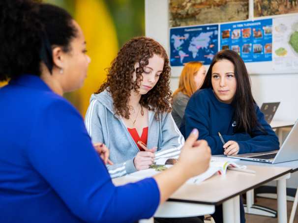 2 leerlingen krijgen uitleg aan tafel van een docenten op het Citadel College. 