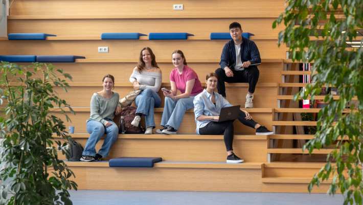 Een docent legt drie studenten iets uit.