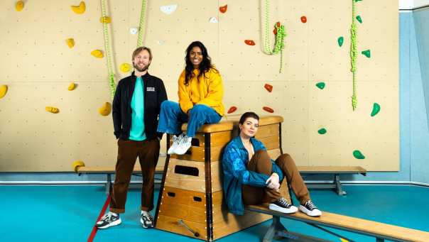 3 studenten Sport en Bewegen in een gymzaal bij de klimmuur.