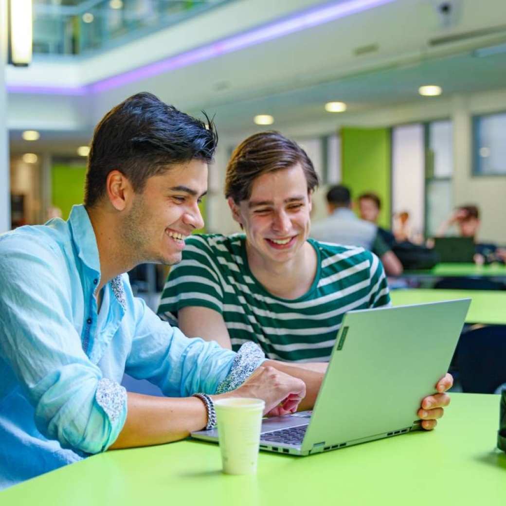 twee personen van Commerciële Economie kijkende naar een laptop