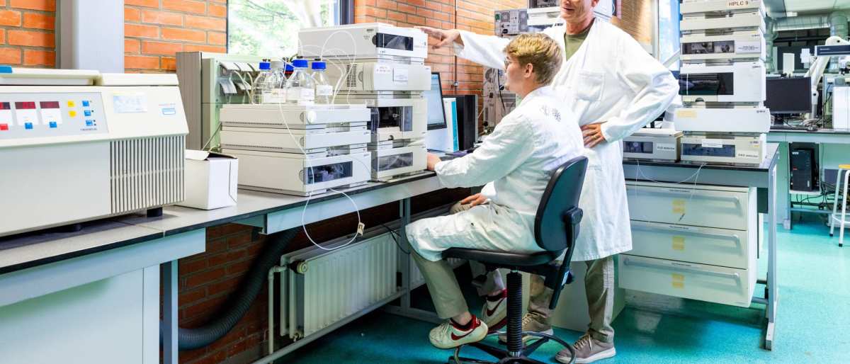 docent geeft uitleg aan student in chemie lab