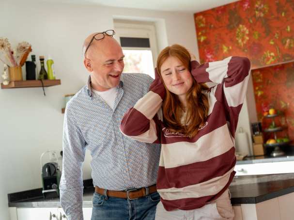 Vader wil in gesprek, terwijl de dochter er niks van wil horen en haar handen op haar oren houdt.