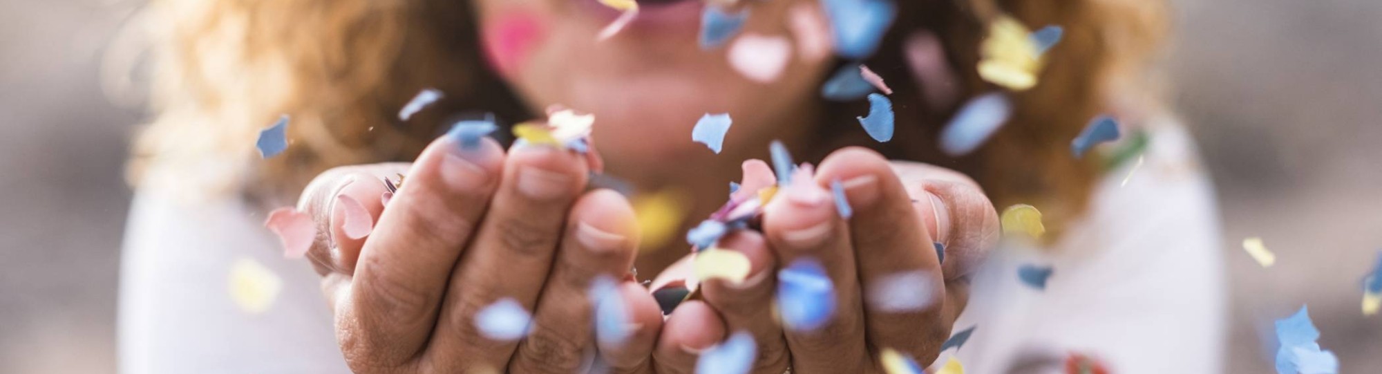 vrouw met confetti in handen en blaast