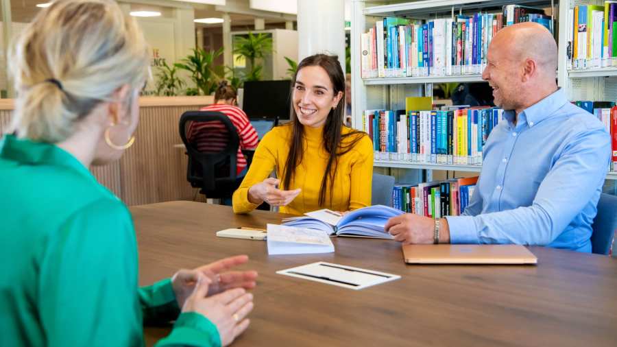 Student in overleg met twee docenten van de opleiding Bedrijfskunde deeltijd in gesprek op de HAN-campus in Arnhem, Ruitenberglaan 31. Ze lachen. 