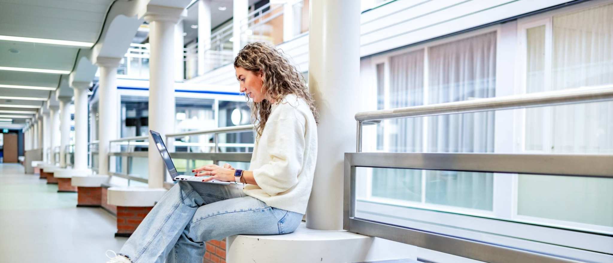 Student van de bachelor Commerciële Economie deeltijd, duaal in gang met laptop.