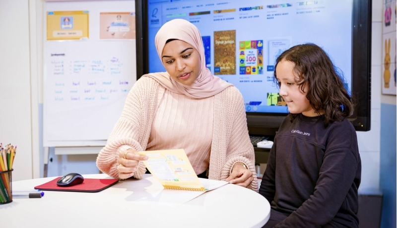 Lerares legt iets uit aan een leerling op de basisschool.