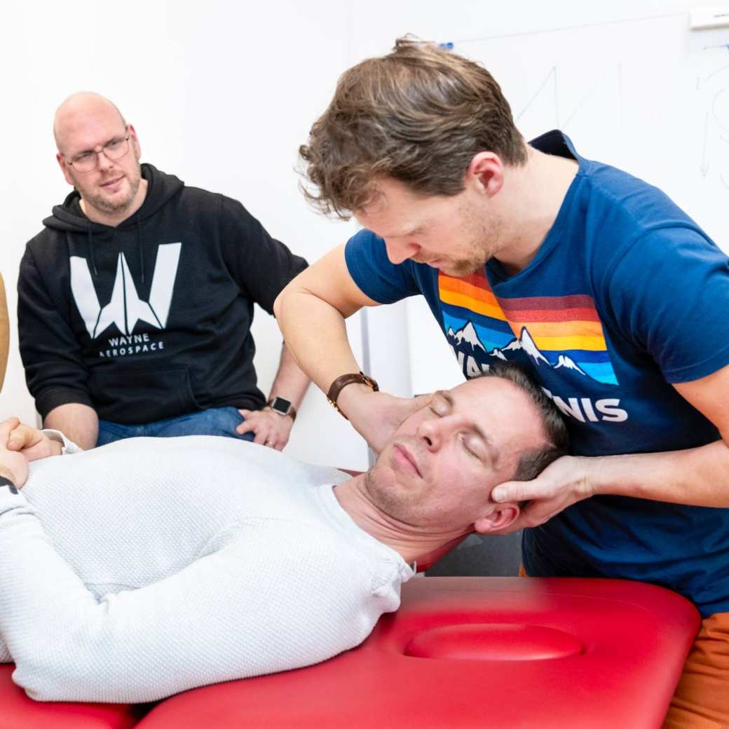 Student draait het hoofd van iemand die op een behandeltafel ligt.