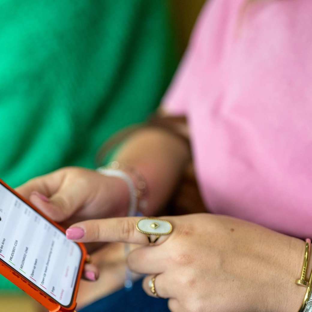 Student houdt haar telefoon vast en wijst er met haar vinger iets op aan.