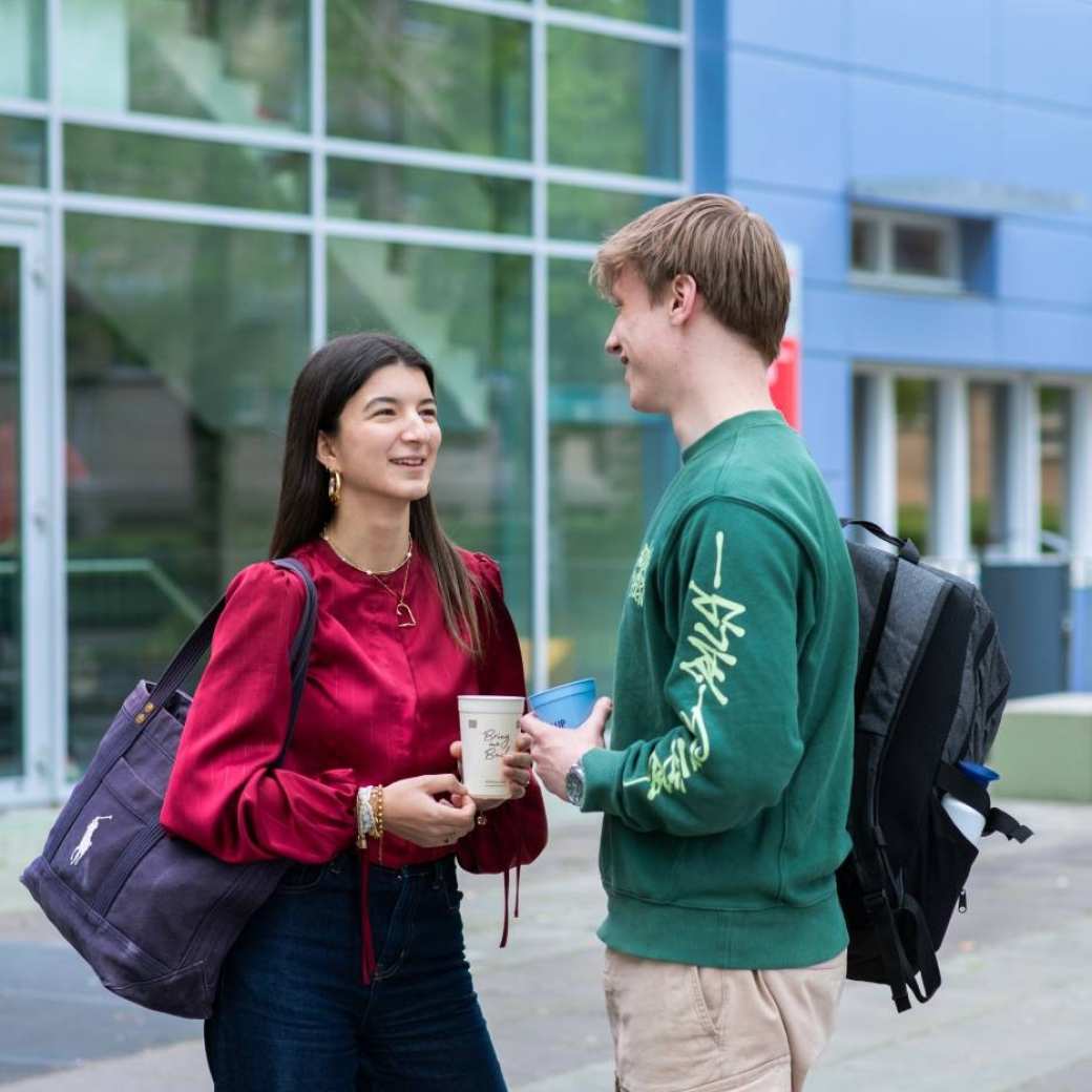 Twee studenten hbo Toegepaste Psychologie kletsen buiten op de HAN campus