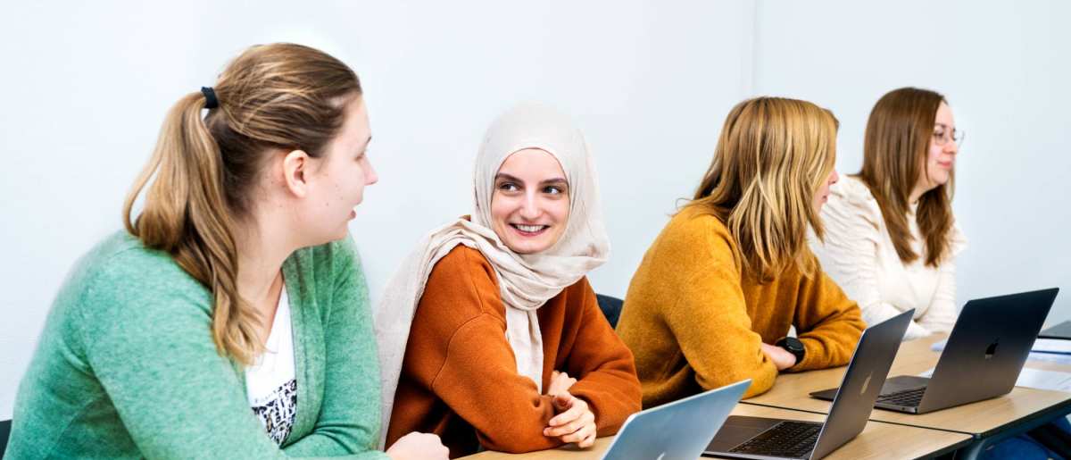 Studenten met laptop aop tafel tijdens een les.