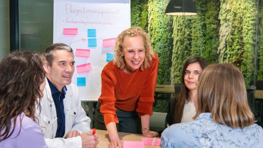 Deelnemers en docenten van de post-hbo Bedrijfskunde in overleg, lachend.