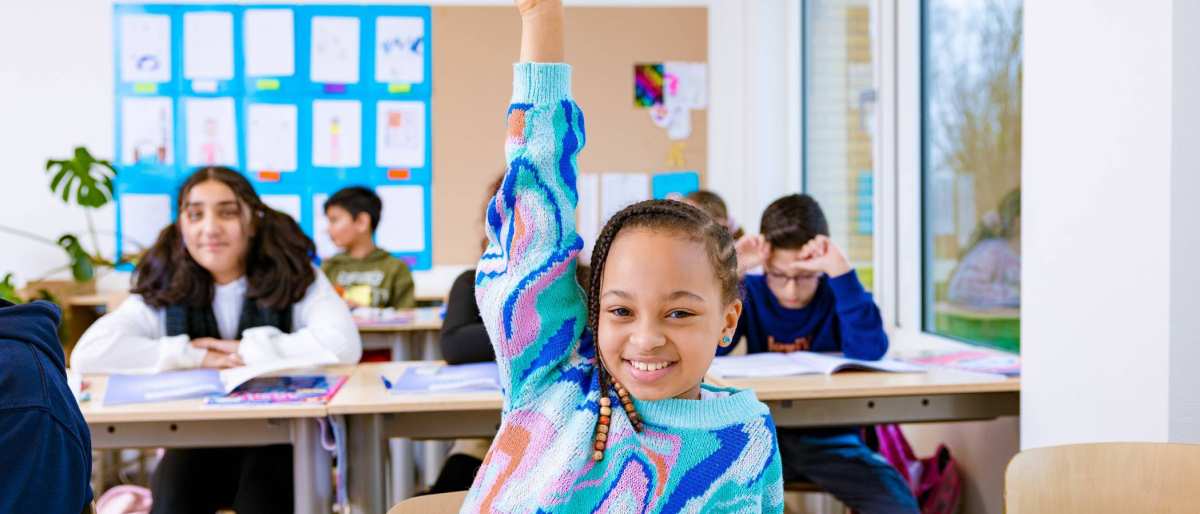 Groep 5,6,7 op de school Da Vince. Een meisje steekt in de klas haar vinger op.