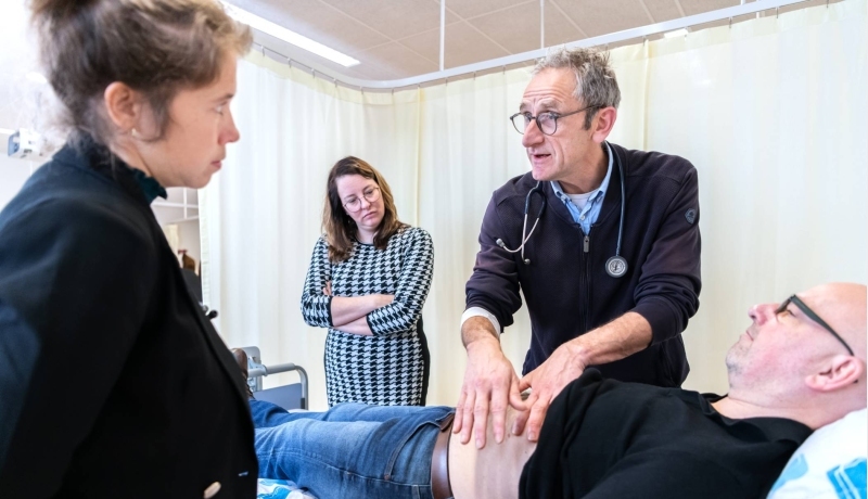 docent van de han master physician assistant geeft uitleg aan 2 studenten over een medische handeling bij een patient op de onderzoeksbank
