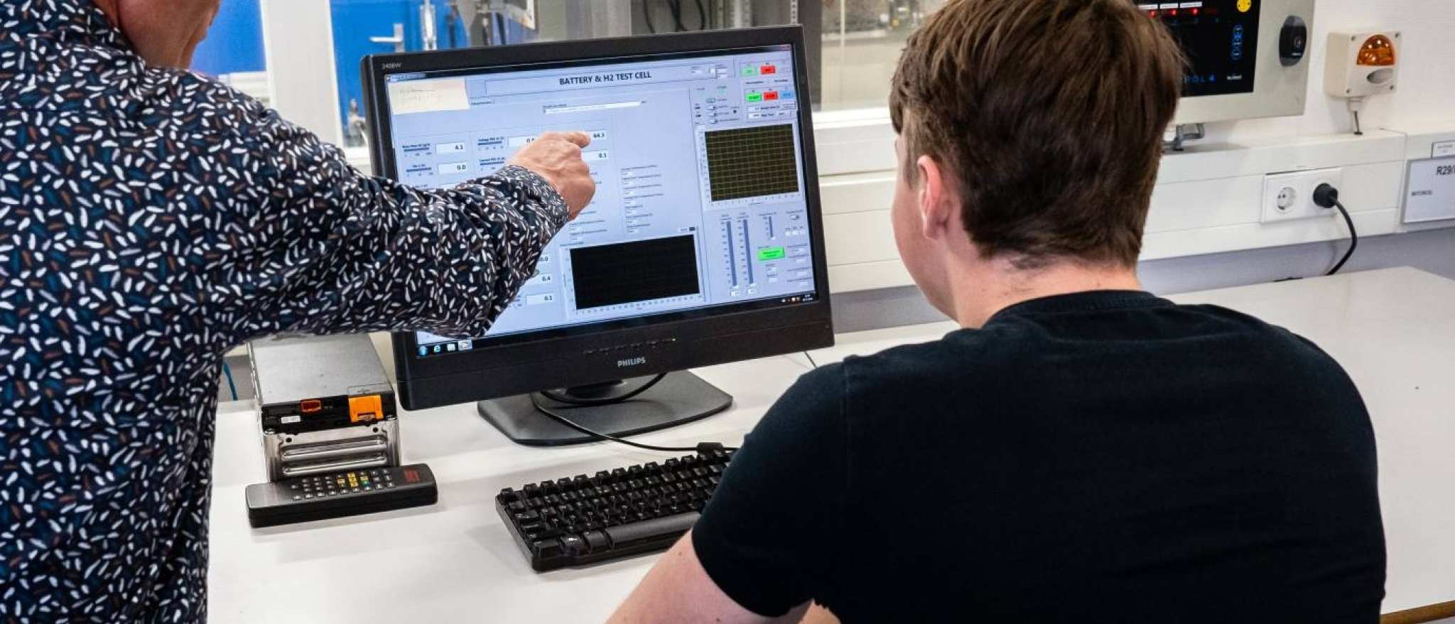 Automotive docent geeft aanwijzingen aan een student bij de waterstoftafel.