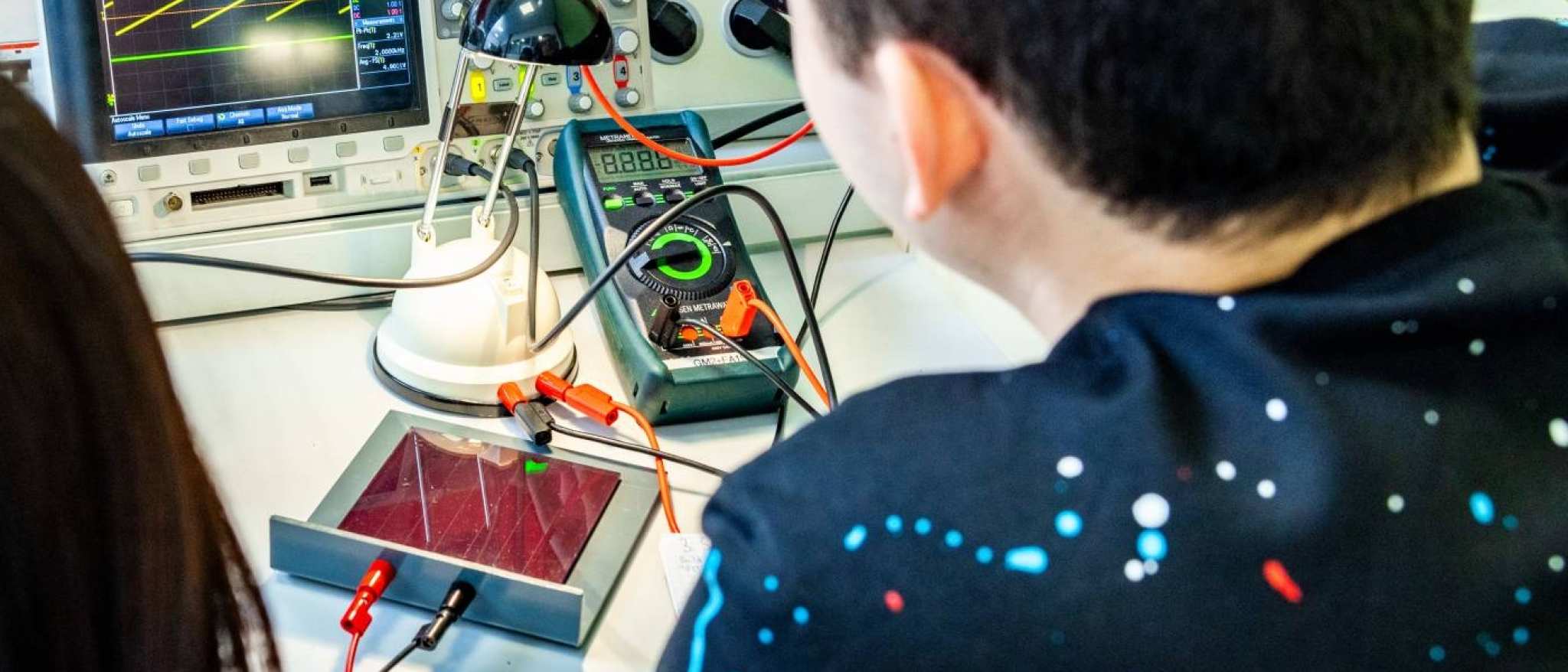 Twee studenten elektrotechniek doen een experiment met een zonnepaneel.