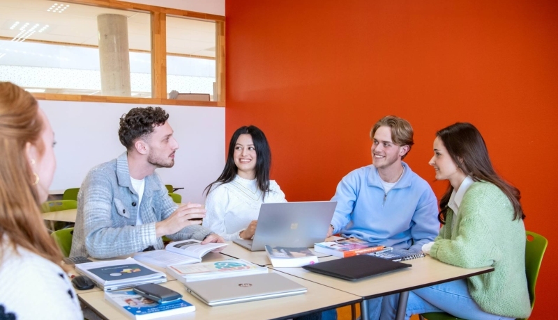 Studenten leraar economie overleggen in de klas.