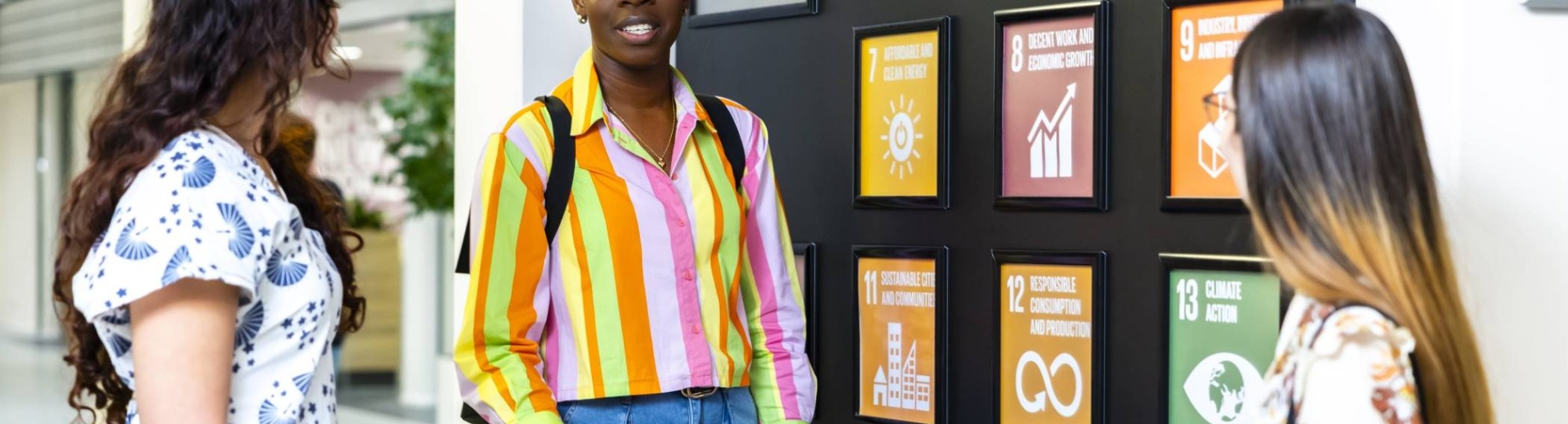 Studenten bij plaatjes van SDG's die op de muur geplakt zijn
