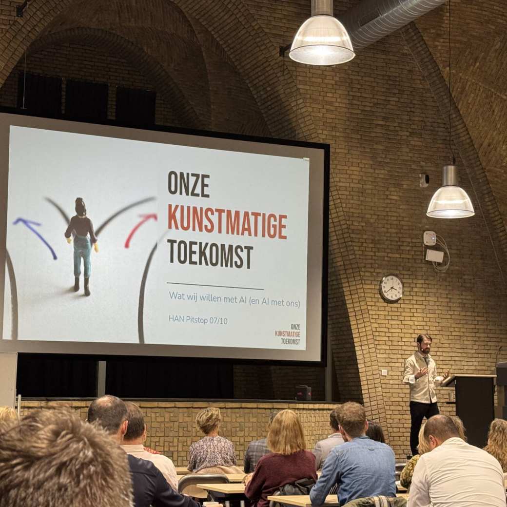 Foto van de Pitstop Onze Kunstmatige Toekomst. In de grote zaal in het Albertinum luisteren de bezoekers naar de presentatie van Joris Krijger.