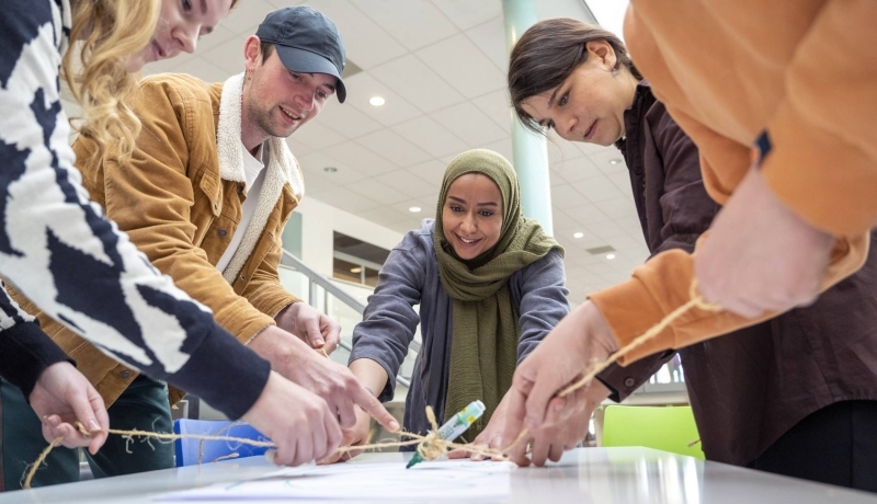 Groep studenten met een docent spelen een spel met een stift. (verzadiging en kleurbalans bewerkt)