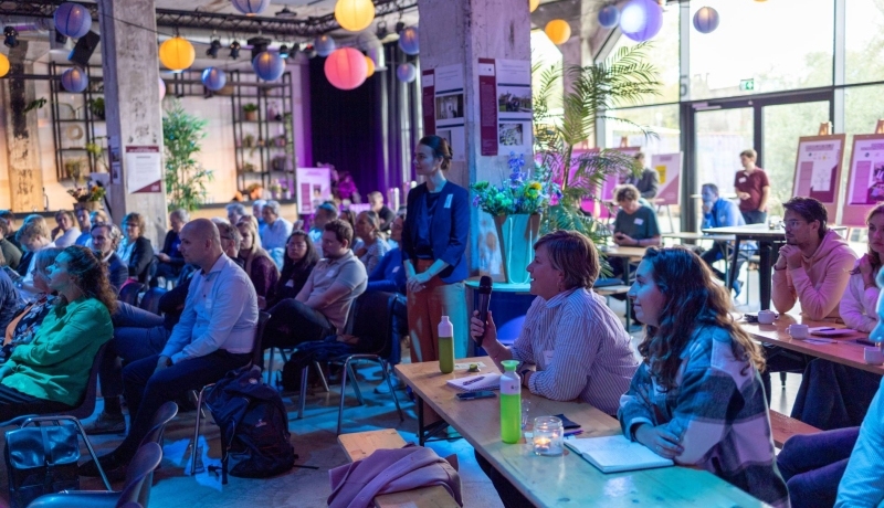 Symposium Nieuwe Wonen 2023. Mensen luisteren naar sprekers.