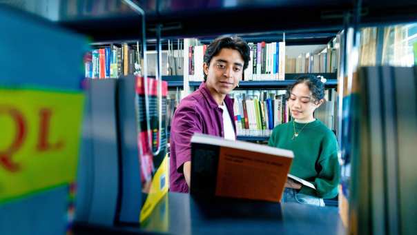 International students Diego and Tam looking for books in the library on the Arnhem campus of HAN University of Applied Sciences.
