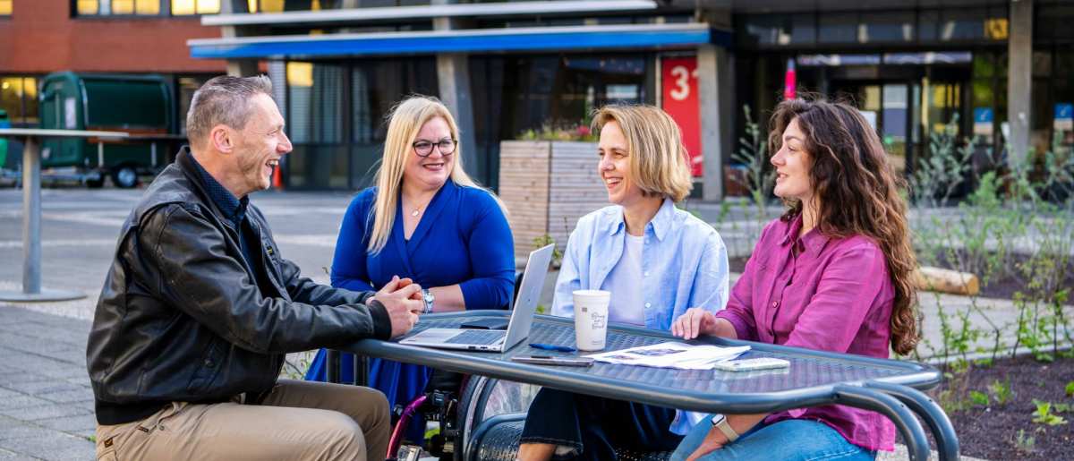 Deelnemers en docenten van de post-hbo Bedrijfskunde in overleg, lachend.